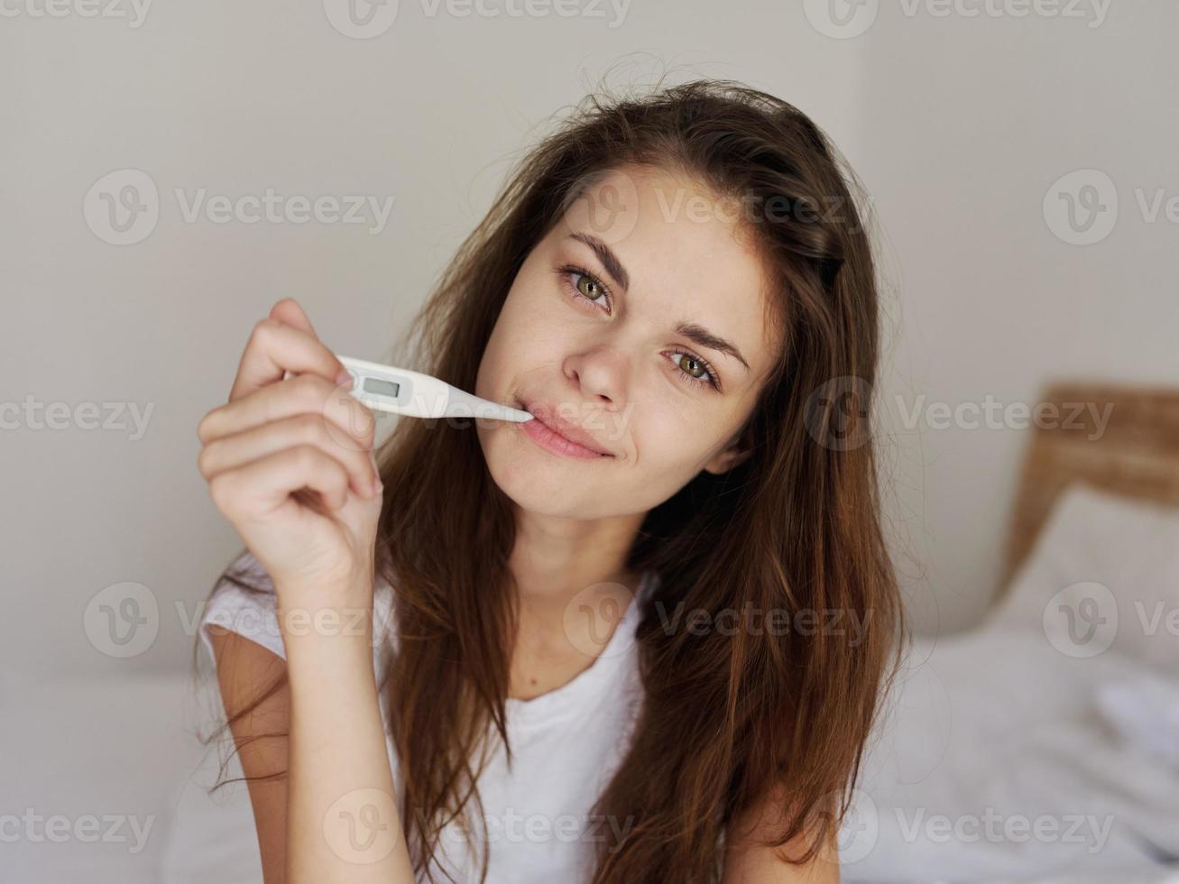 mulheres Verifica temperatura com uma termômetro dentro seus boca dentro a quarto foto