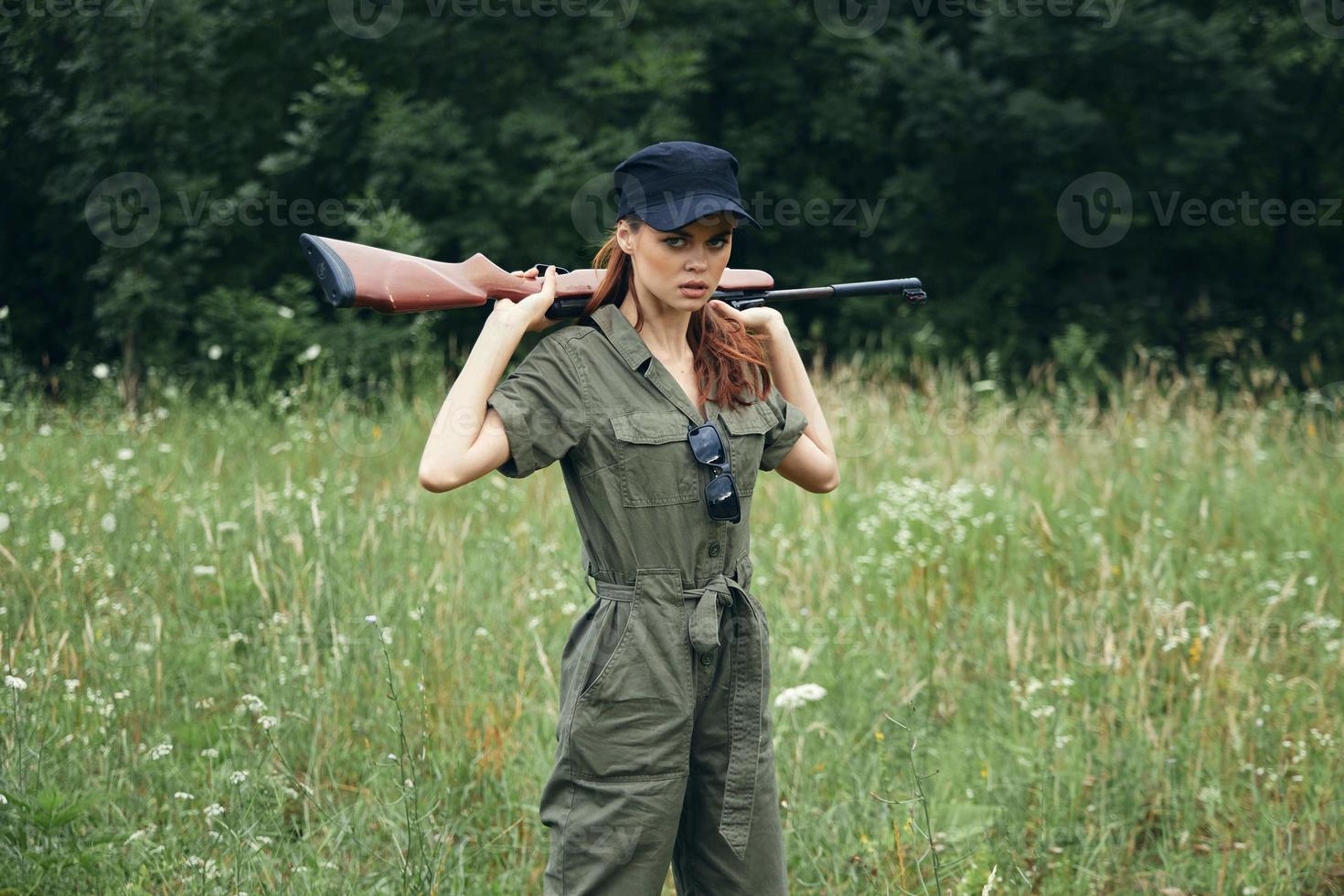 mulher soldado com uma arma dentro dele mãos uma verde macacão e uma Preto boné armas foto