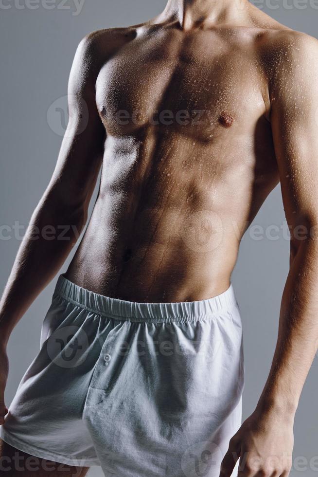 desportivo masculino fisiculturista com abdômen cubos em estômago cinzento fundo branco calção foto