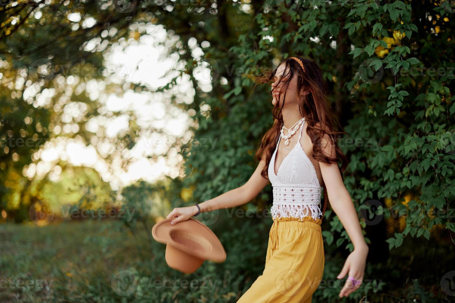 uma mulher dentro ecológico roupas dentro uma hippie Veja danças dentro natureza dentro a parque e sorrisos às a mundo. a conceito do harmonia com a corpo e a em torno da natureza foto