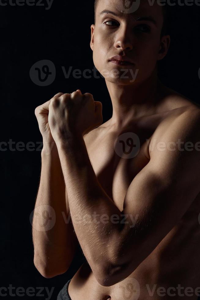 desportivo cara com bombeado acima braço músculos em uma Preto fundo olhando para a lado fechar-se foto