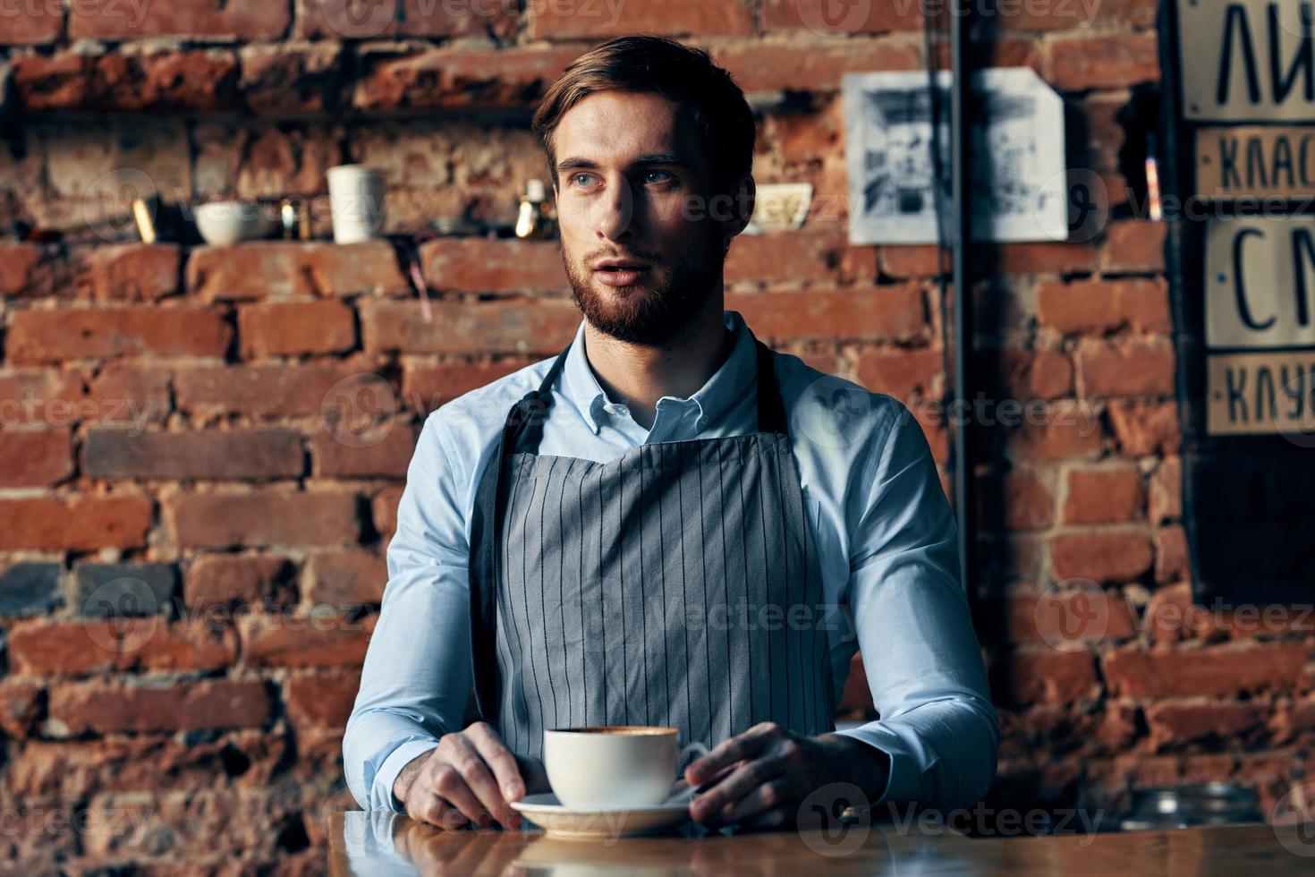 masculino garçom avental serviço café copo tijolo parede foto