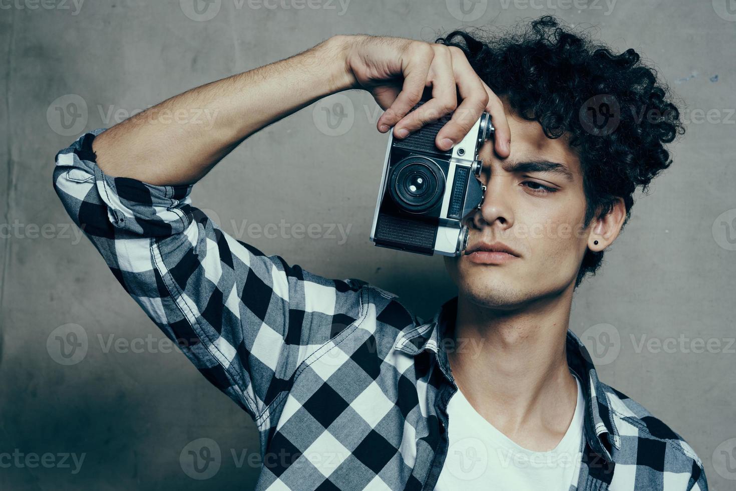 bonito cara com uma Câmera perto dele face e encaracolado cabelo xadrez camisa passatempo fotógrafo foto