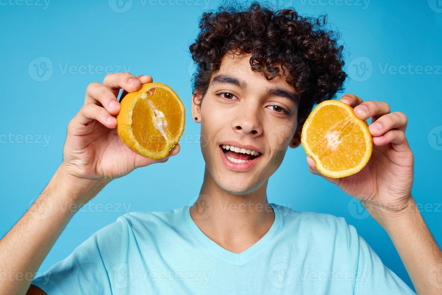 homem com encaracolado cabelo segurando laranjas fruta azul fundo foto