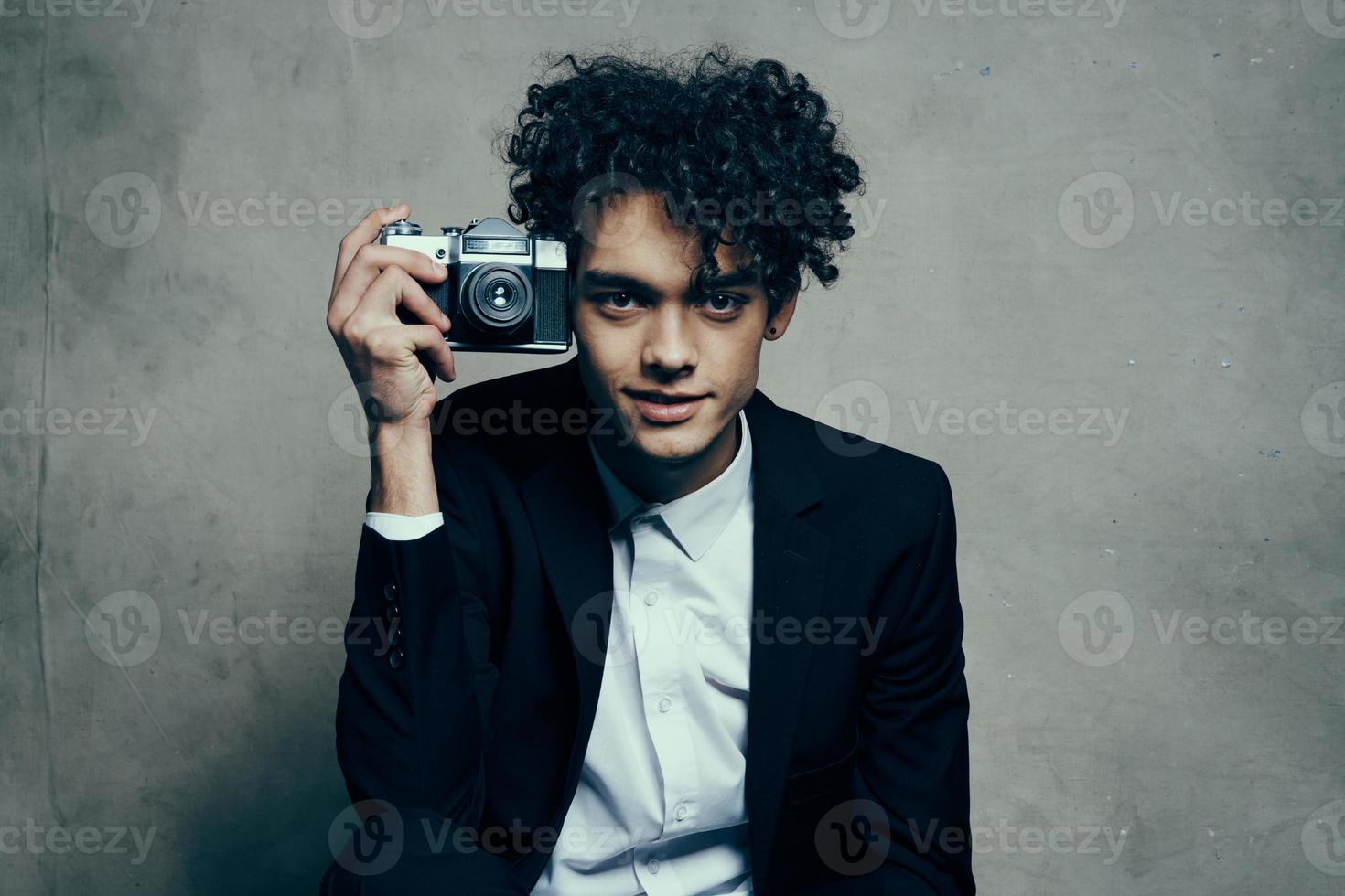 cara segurando uma Câmera dentro dele mão retro clássico terno encaracolado modelo homem foto