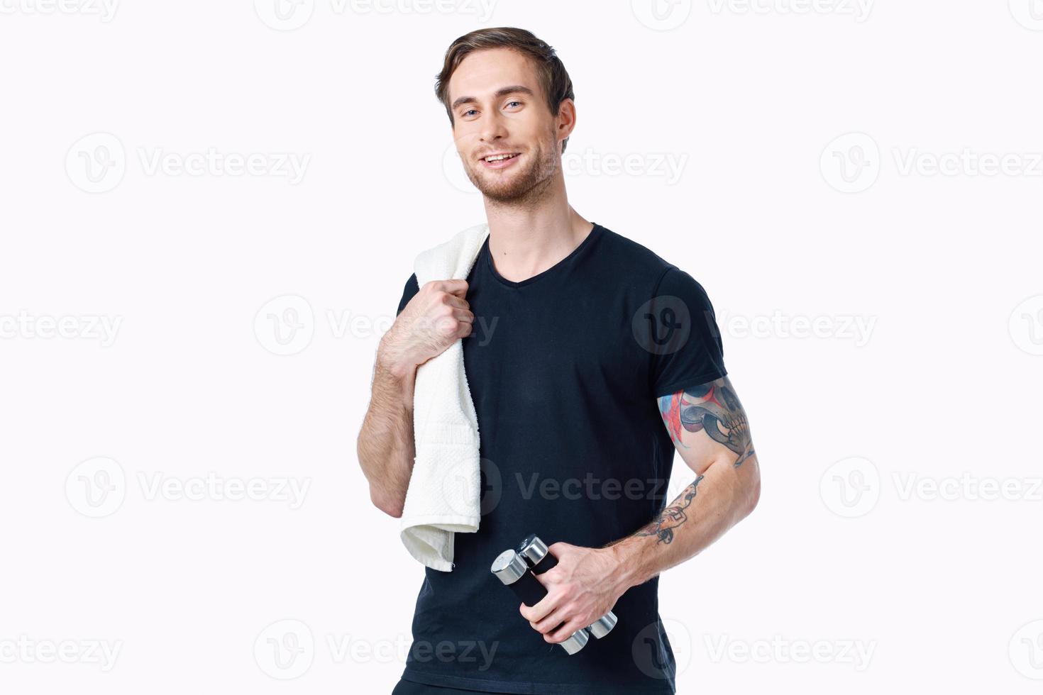 atleta dentro uma Preto camiseta com halteres em uma branco fundo tatuagem em dele braço e uma toalha foto