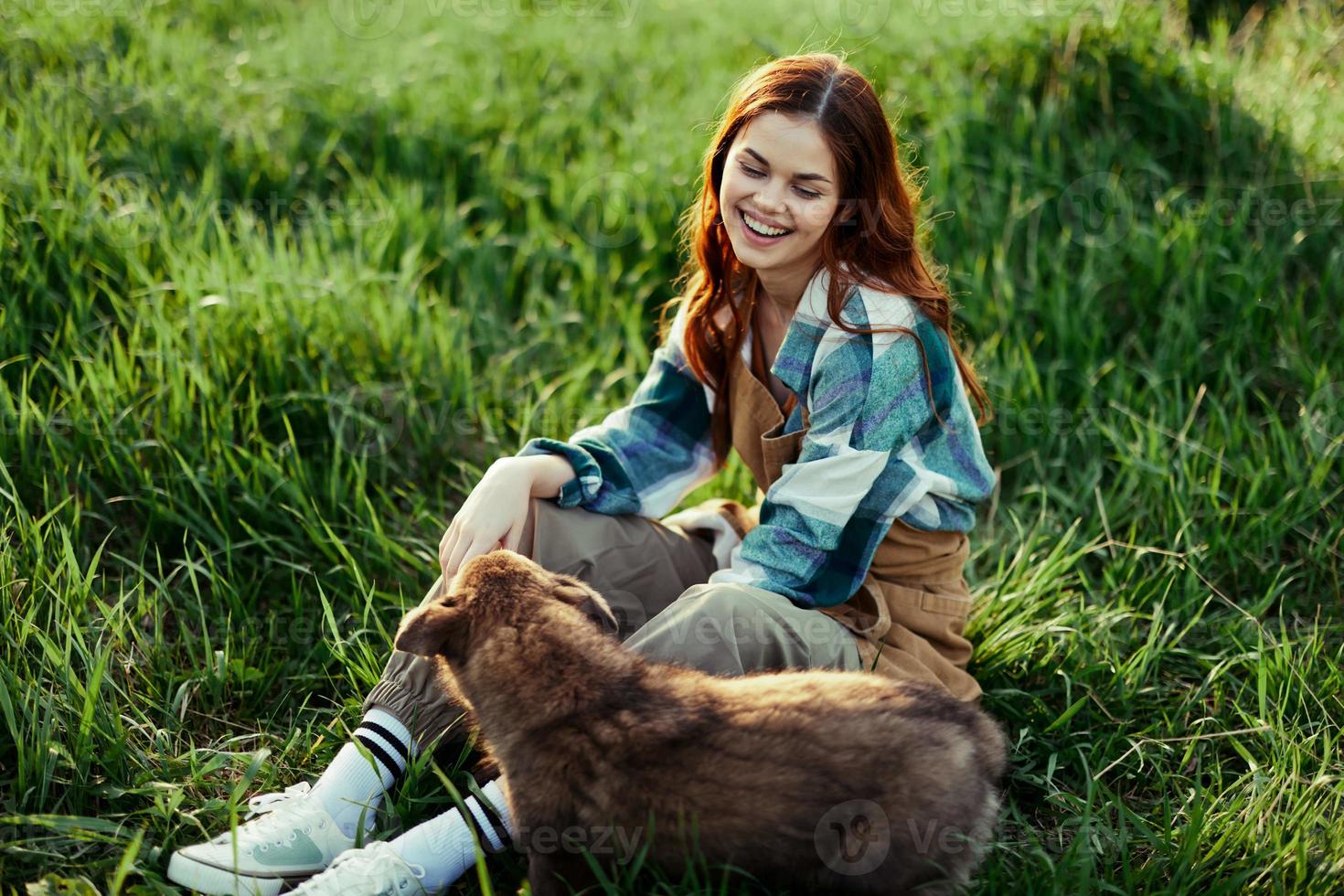 mulher alegremente sorridente às jogando com dela pequeno cachorro ao ar livre em fresco verde Relva dentro a verão brilho do sol dela e dela cachorro saúde, saúde conceito e oportuno tratamento para insetos carrapatos e Carraça pulgas foto