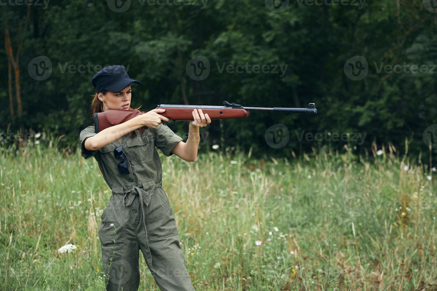 mulher soldado ele detém uma arma de fogo dentro dele mãos visando às uma alvo verde folhas verde foto