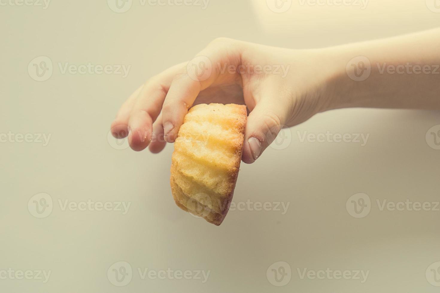 saboroso pequeno Páscoa Bolinho em uma criança mão em uma luz fundo foto