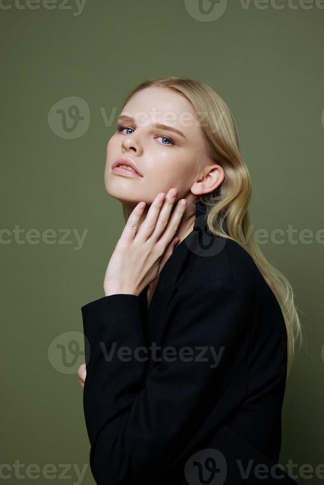 atraente lindo brilhante menina parece para dentro a Câmera posando dentro a estúdio dentro uma terno em uma verde fundo foto