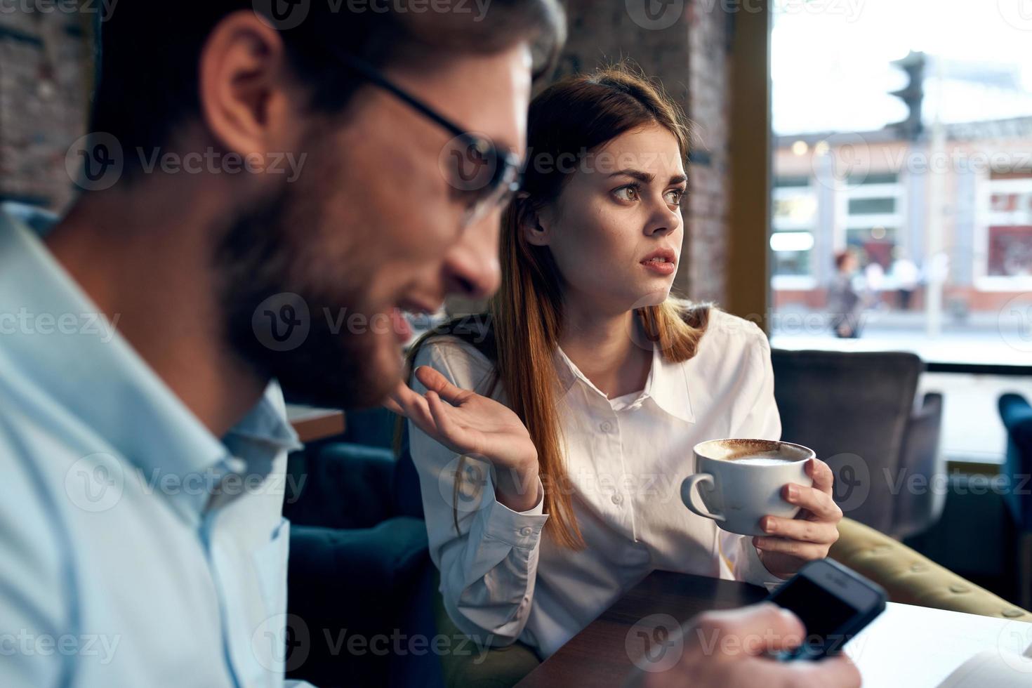 o negócio homens e mulheres sentar às a mesa com a telefone conversando café da manhã foto