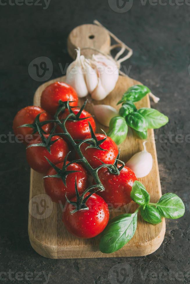 orgânico produtos - tomate, manjericão, alho em corte borda em Sombrio sobrancelha concreto pedra fundo foto