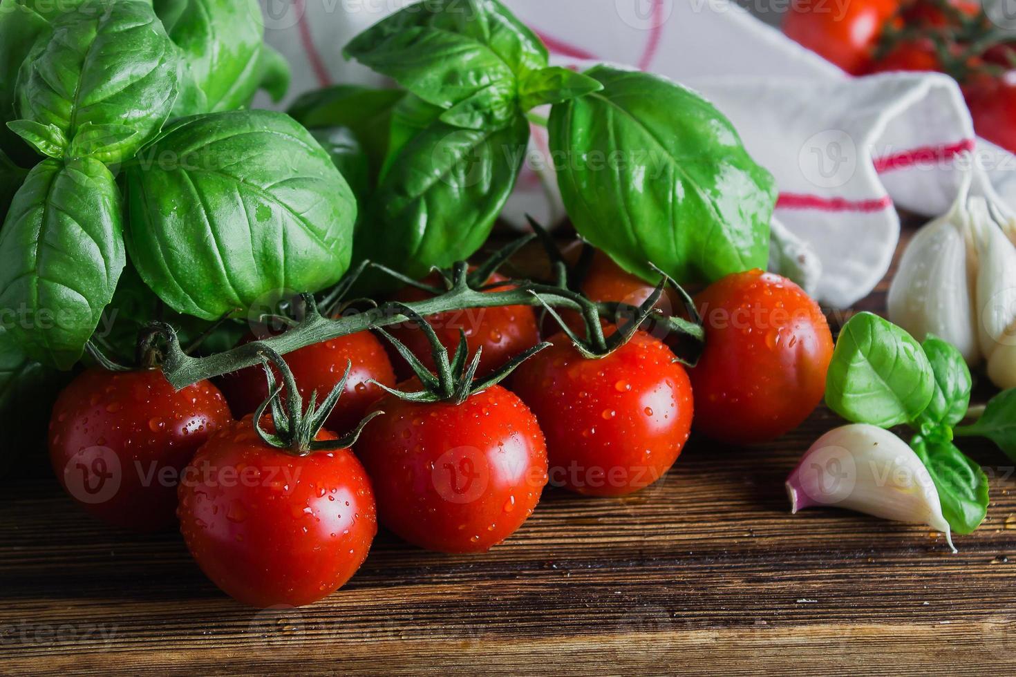 cereja tomates com manjericão folhas em de madeira borda em Sombrio pedra fundo. saudável nutrição orgânico Comida conceito. fechar-se foto