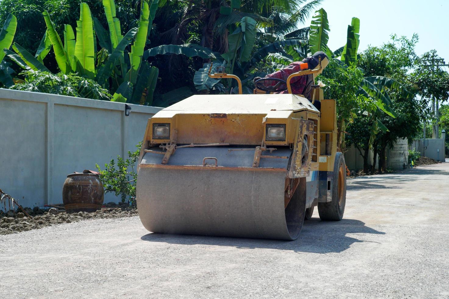 trabalhador dirige o rolo-compactador na estrada de pedra para preparar a superfície foto