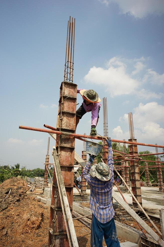 Ratchaburi, Tailândia 2018 - grupo de trabalhadores constrói a fundação de uma casa despejando o cimento misturado no modelo de madeira no local da construção foto