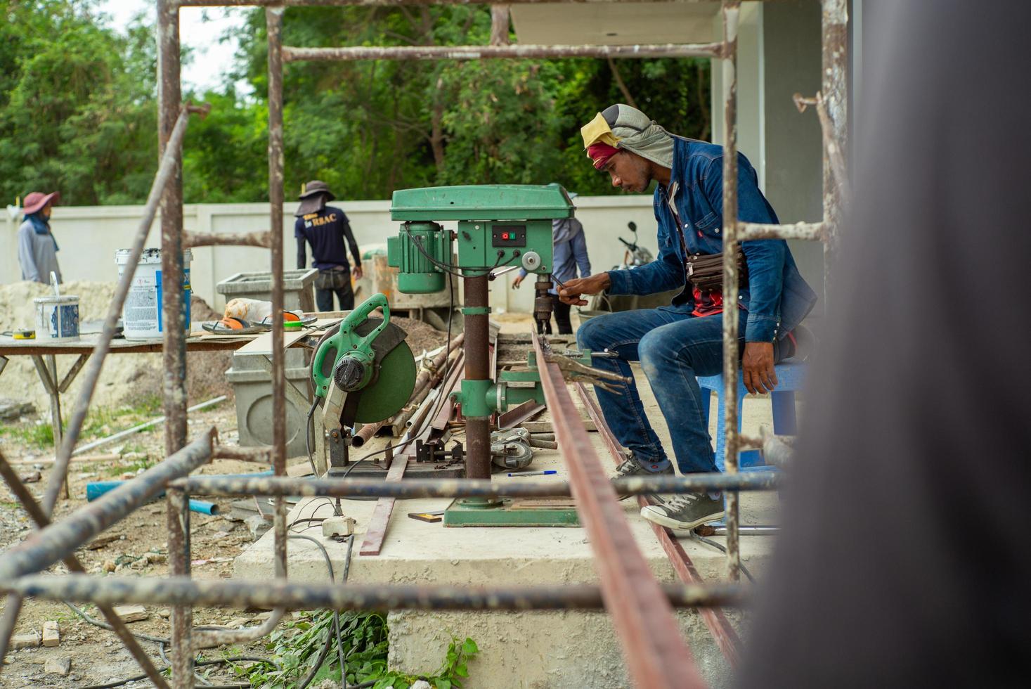 Ratchaburi, Tailândia 2019 - trabalhadores usam uma furadeira elétrica para fazer um furo na viga angular de aço foto