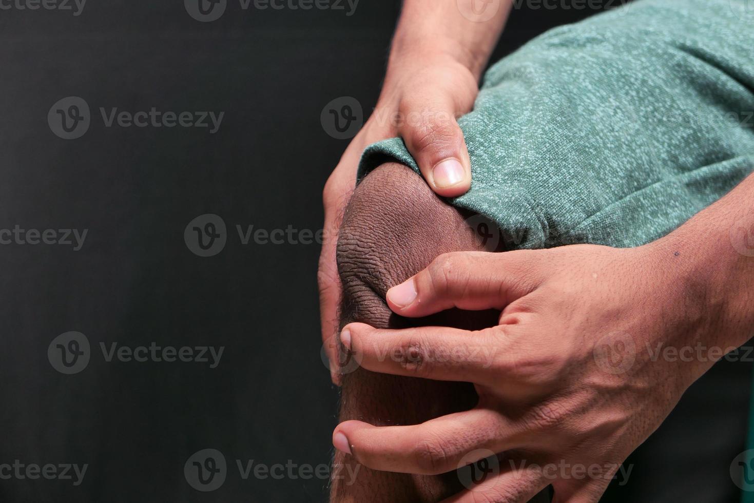 close-up de um homem sofrendo de dor nas articulações do joelho isolada em preto foto