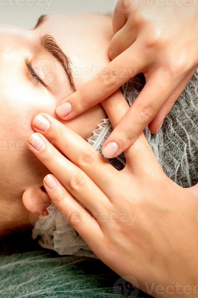 jovem mulher recebendo facial massagem foto