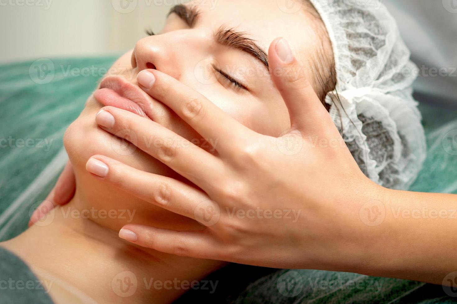 jovem mulher recebendo facial massagem foto