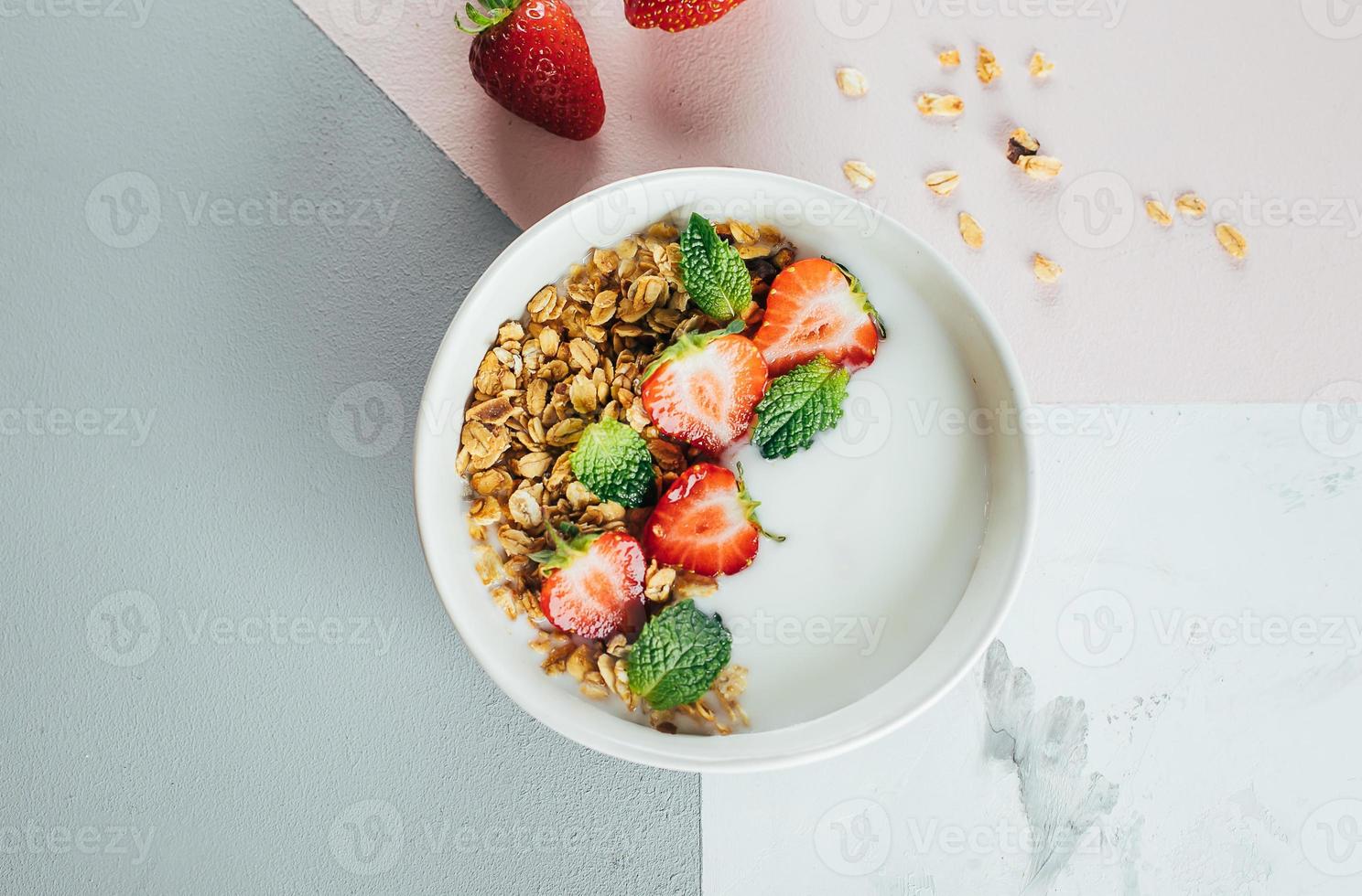 plano deitar Comida conceito. saudável café da manhã. branco tigela com iogurte, caseiro granola, morangos foto