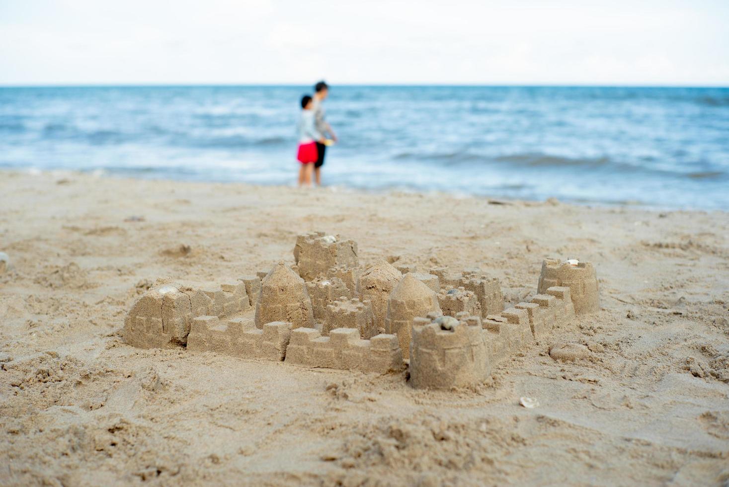 o castelo de areia construído usando o molde com pessoas desfocadas no fundo foto