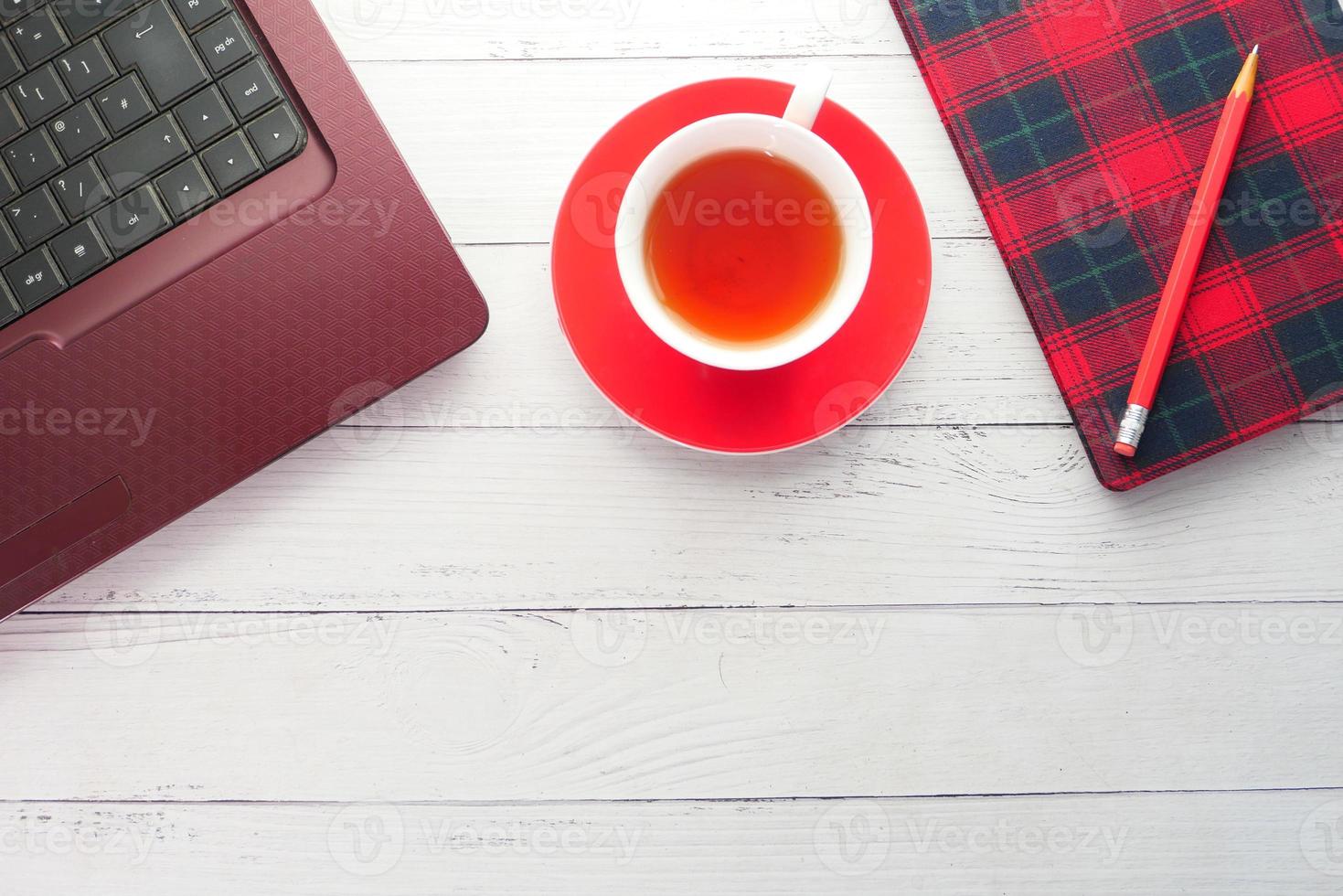 chá quente, laptop e um notebook em uma mesa foto