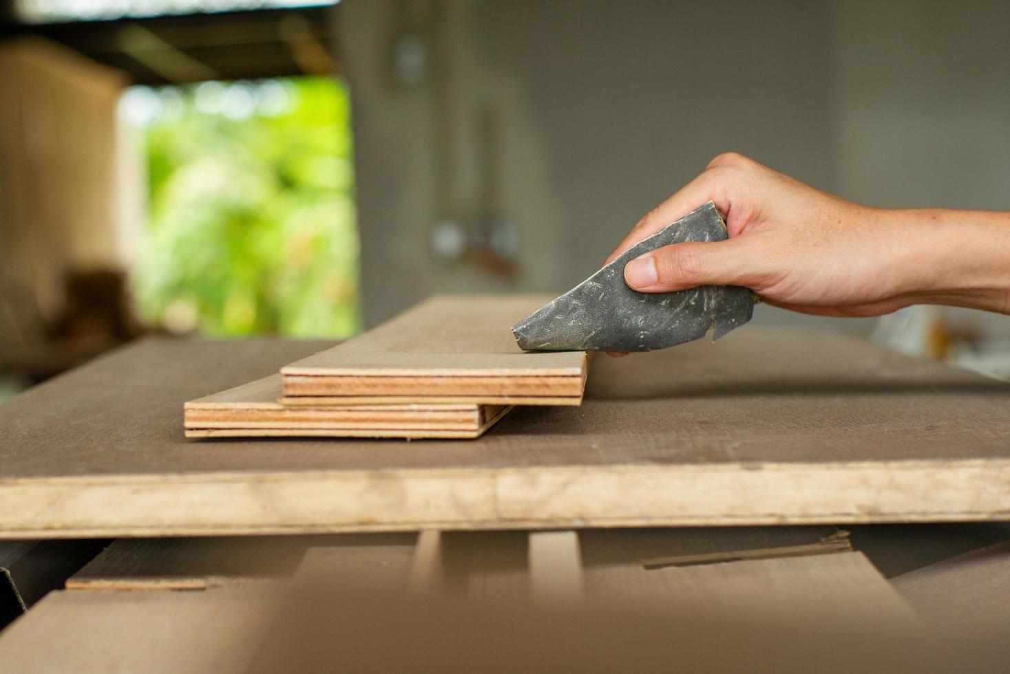 foco seletivo na mão do carpinteiro esfregando a superfície da madeira na fábrica foto