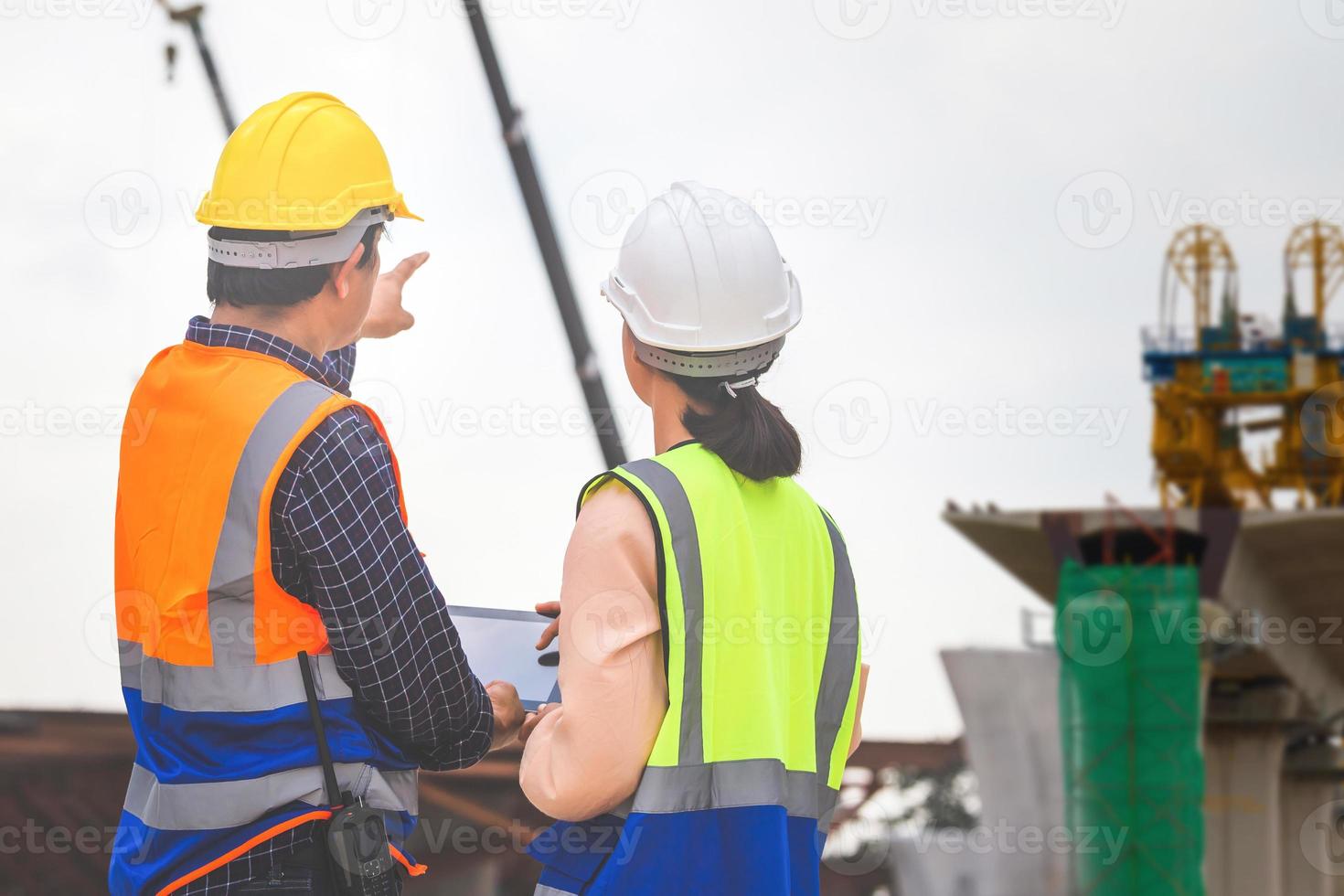 fêmea engenheiro e capataz trabalhador verificação projeto às construção site, engenheiro e construtores dentro capacetes discutindo em construção site, trabalho em equipe conceitos foto