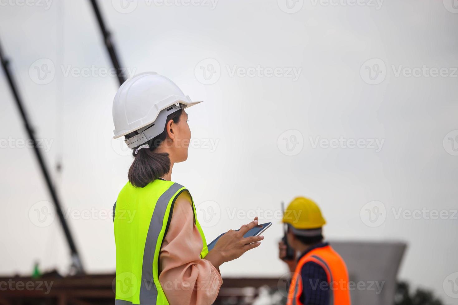 fêmea engenheiro e capataz trabalhador verificação projeto às construção site, engenheiro e construtores dentro capacetes discutindo em construção site, trabalho em equipe conceitos foto