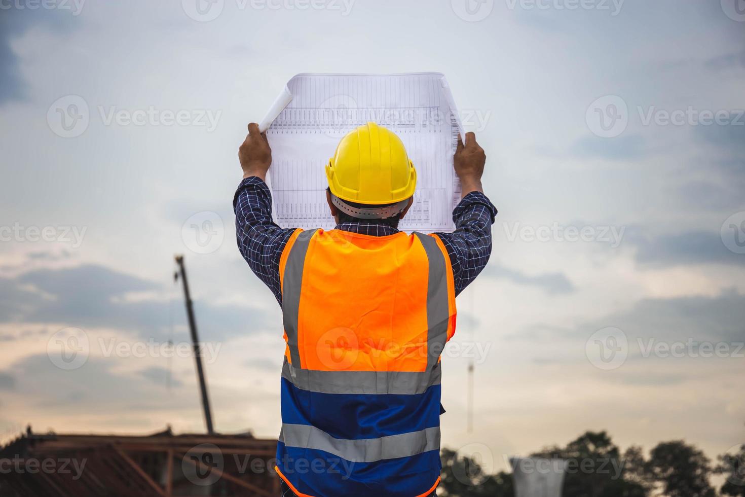 engenheiro de construção, verificando o projeto no canteiro de obras, arquiteto com plantas em um canteiro de obras, capataz trabalhador no capacete de segurança no canteiro de obras de infraestrutura foto