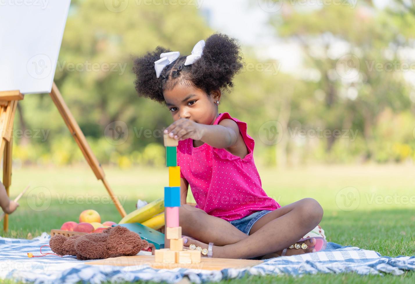 fofa pequeno menina jogar brinquedo às a jardim, criança menina jogando com pequeno de madeira brinquedo ao ar livre foto