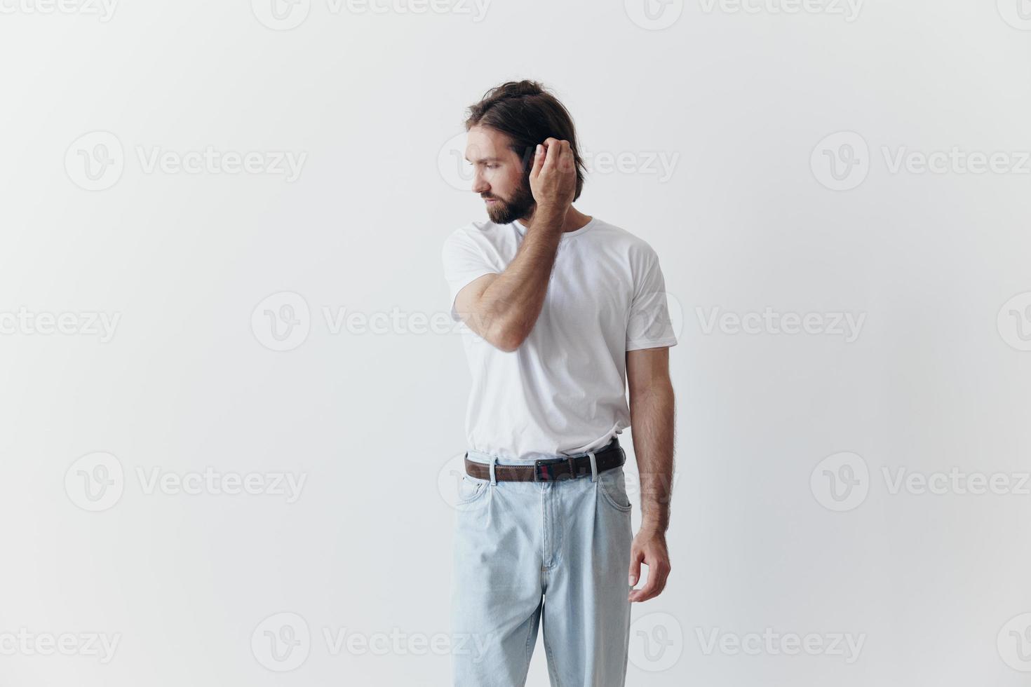 retrato do uma homem com uma Preto Grosso barba e grandes cabelo dentro uma branco camiseta em uma branco isolado fundo emoção do tristeza e anseio foto