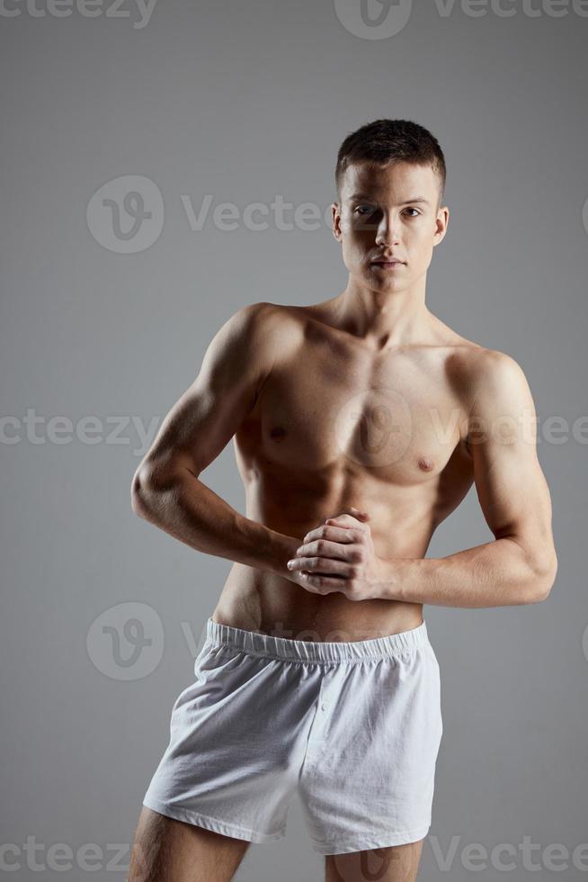 atleta com inflado tronco juntou mãos perto peito em cinzento fundo cortada Visão foto