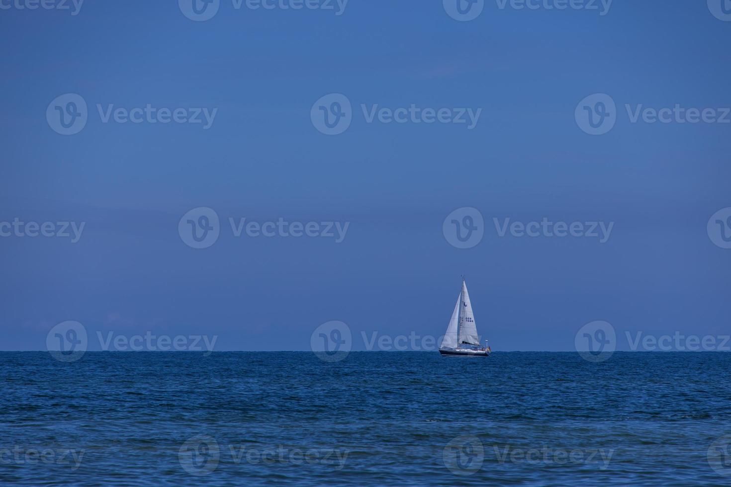 verão panorama a partir de a báltico mar com azul água e céu e uma branco barco a vela foto