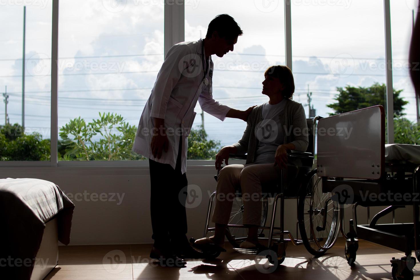 caucasiano homem médico é examinando a fêmea Mais velho paciente dentro cadeira de rodas a hospital. foto