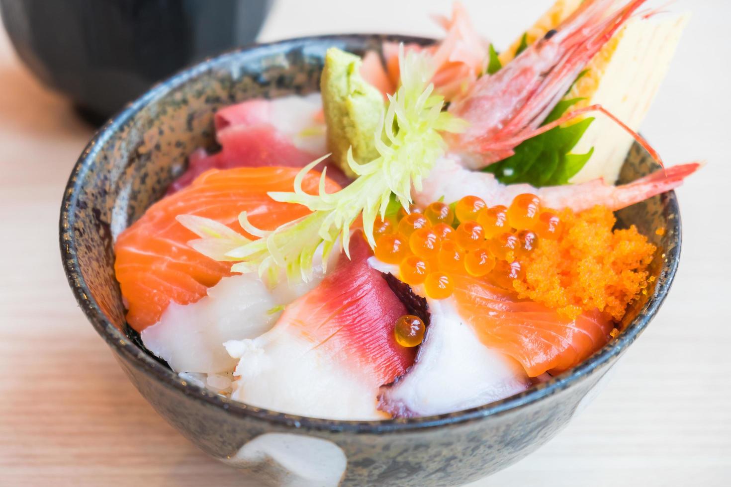 tigela de arroz japonês com sashimi de frutos do mar por cima foto