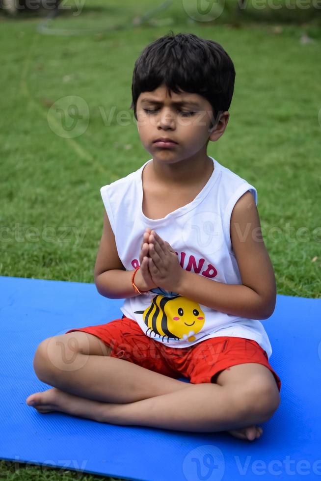 ásia inteligente criança fazendo ioga pose dentro a sociedade parque ar livre, crianças ioga pose. a pequeno Garoto fazendo ioga exercício. foto