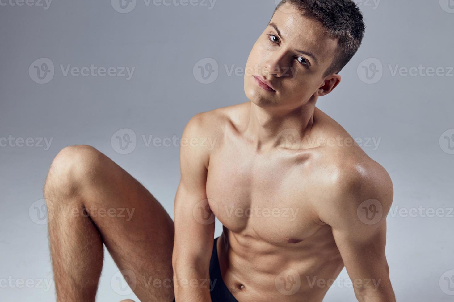 bonito masculino atleta com uma bombeado corpo sentado em a chão foto