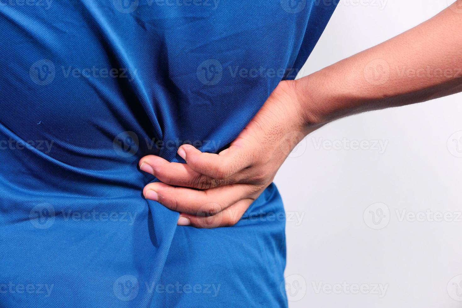 homem de camisa azul se segurando de dor foto