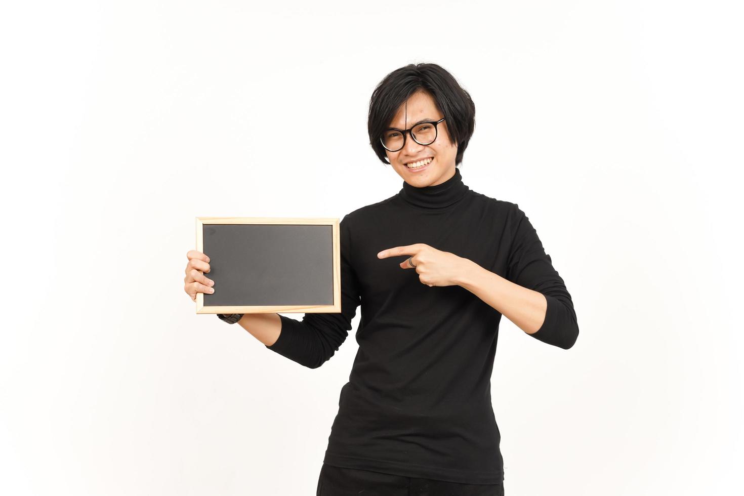 mostrando, apresentando e segurando em branco quadro-negro do bonito ásia homem isolado em branco fundo foto