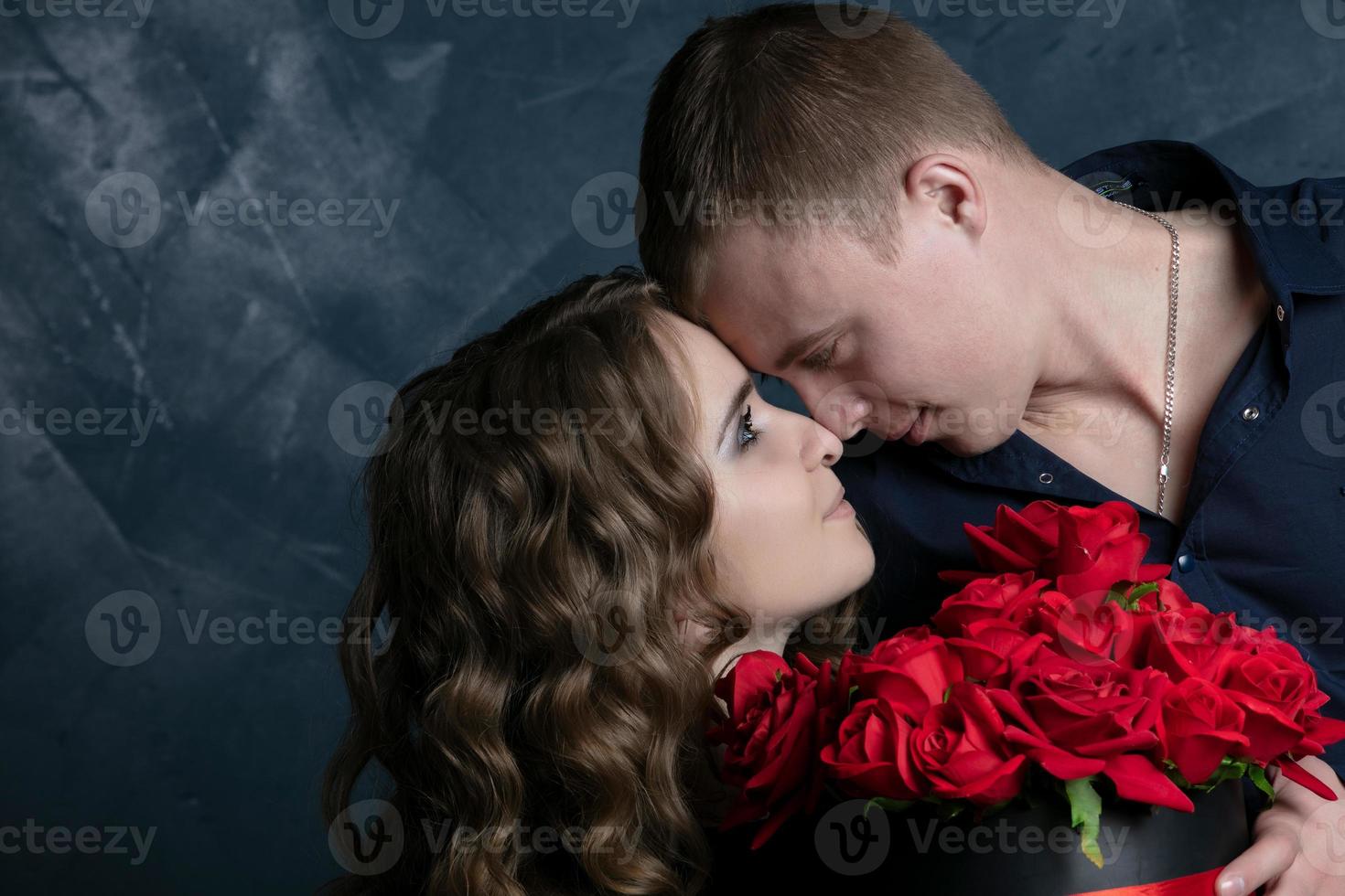 lindo jovem casal .abraços, Beijos e goza gastos Tempo junto, a comemorar dia dos namorados dia com vermelho rosas. foto