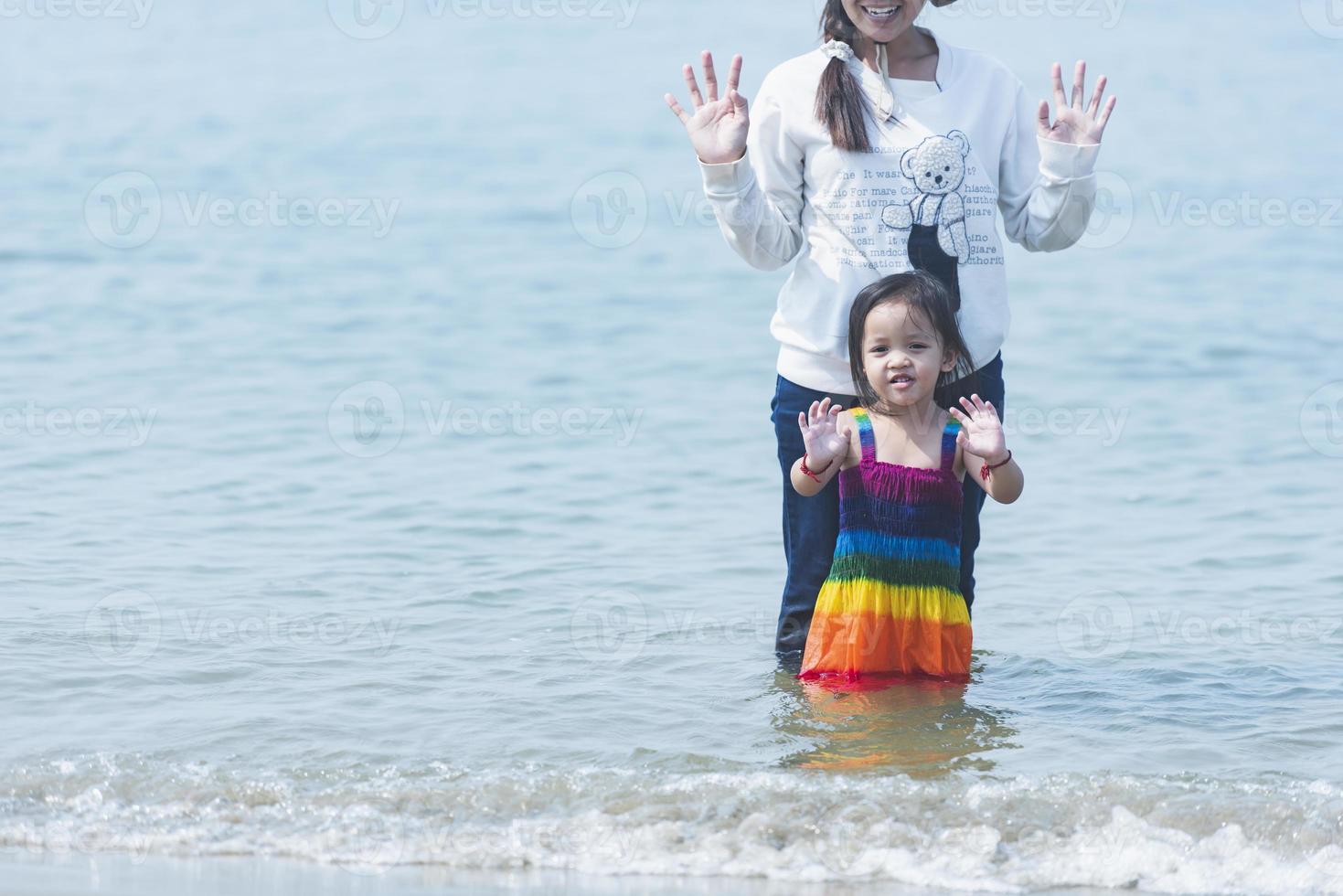 silhueta. mãe e filha jogando em a de praia às pôr do sol. foto