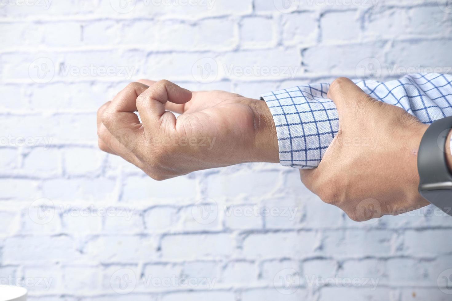 homem sofrendo dor no pulso de perto foto