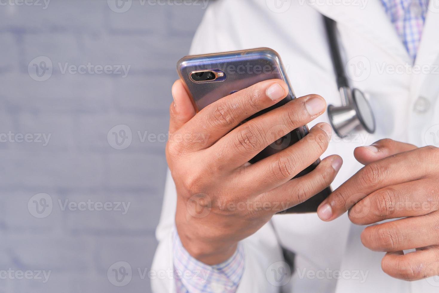 médico de jaleco branco usando um smartphone foto