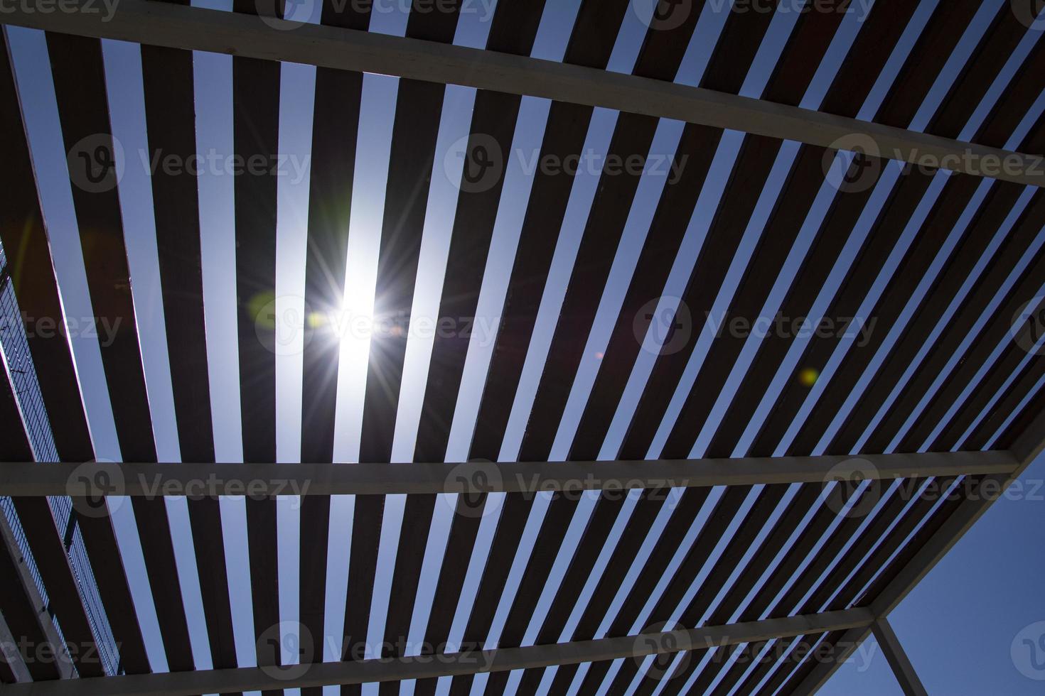 luz solar brilha através a cobertura do uma de madeira pérgola em uma ensolarado dia. foto