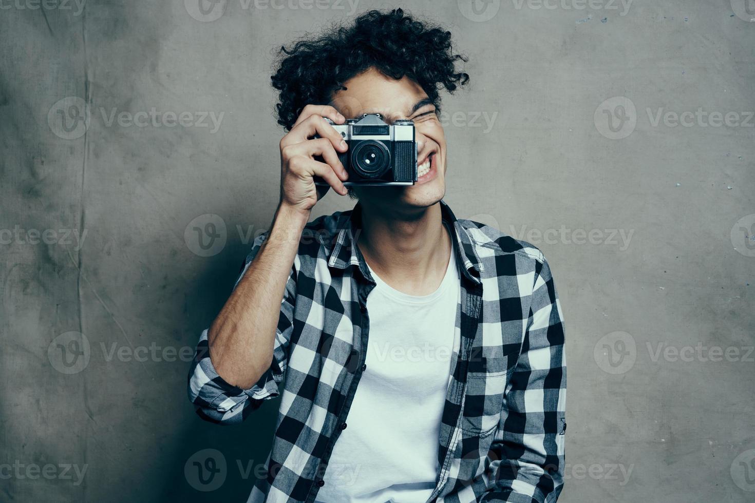 cara com uma Câmera dentro dele mãos em uma cinzento fundo dentro de casa passatempo xadrez camisa modelo foto