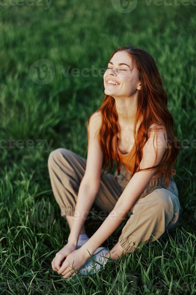 uma jovem mulher dentro verão roupas sentado em a verde Relva fazendo ioga e meditando dentro natureza, uma conexão com a cosmos. a conceito do harmonia com corpo e natureza, espiritual crescimento foto