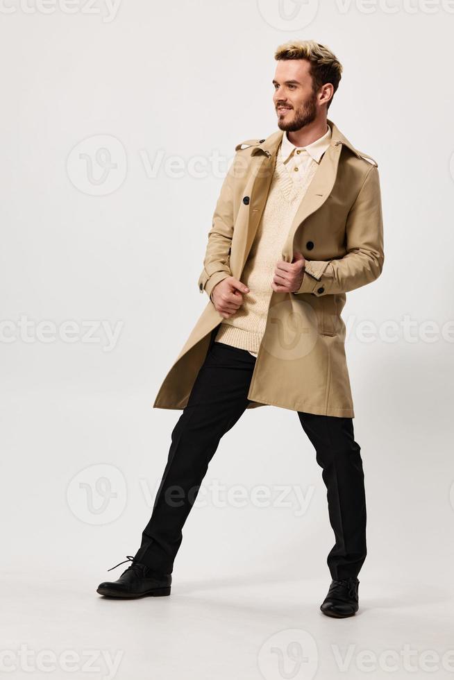 elegante homem dentro uma bege casaco calças em uma luz fundo moda tendência do a estação Primavera foto