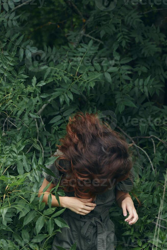 retrato do uma mulher inclinou-se frente e a verde folhas do a arbustos natureza viagem foto