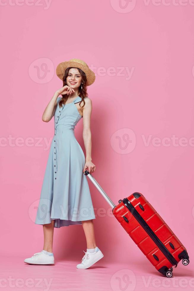 mulher dentro azul vestir com vermelho mala de viagem viagem destino Rosa fundo foto